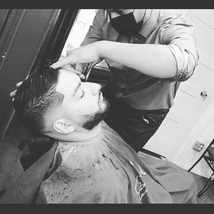 Black and white photo of a barber giving a precision haircut